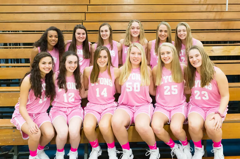 LT basketball team on bleachers in pink shirts