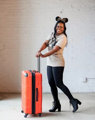 Travel expert with orange suitcase and Minnie Mouse apparel walking
